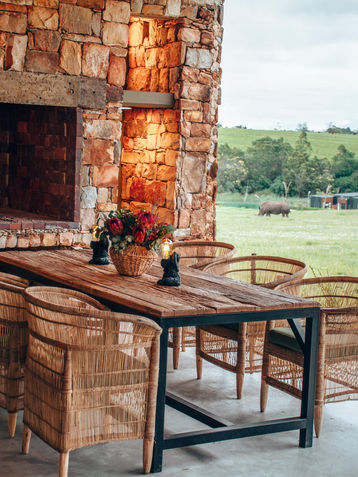 Outdoor patio with fireplace, dining table, and safari view