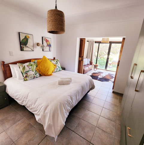 Bedroom with white bed, bird art, and outdoor patio view