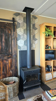 Wood-burning stove with geometric tile wall and wooden bookshelf