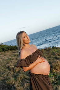 a pregnant lady holding her belly in tall grass