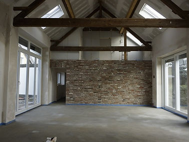 Einblick in einen großen Raum, der sehr modern wirkt aber auch über sehr charakteristische alte Holzbalken verfügt.