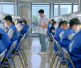 A team of uniformed dental technicians meticulously inspecting finished restorations in a clean, well-lit quality control area at Aceso Dental Lab.