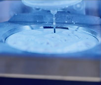 A dental milling machine precisely carving a prosthetic from a block of Zirconia, surrounded by cooling liquid during the manufacturing process.