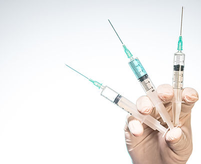 closeup-person-with-latex-glove-holding-three-needle-syringes-against-white-background.jpg