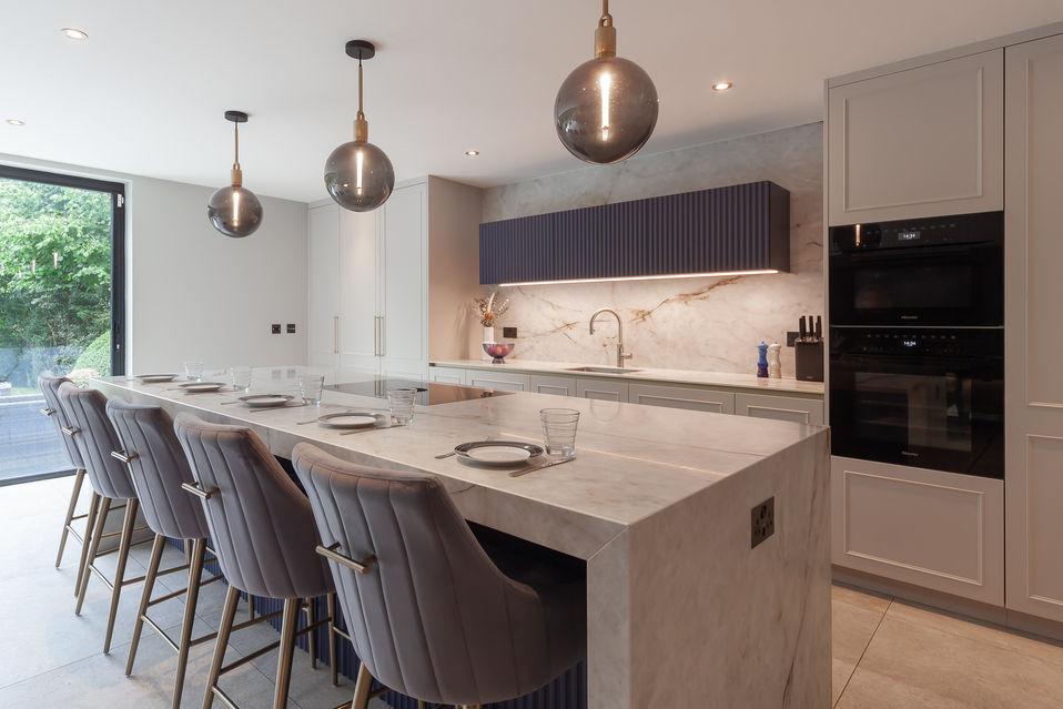 Wide angle of bright bespoke kitchen with island, bar seating and pendant lights in Borehamwood