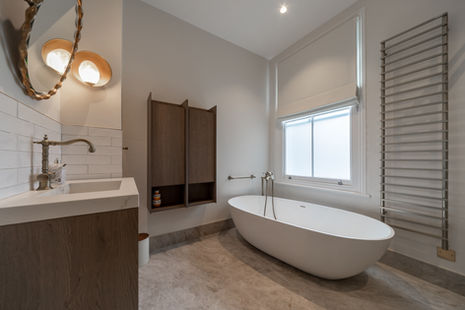 Bright modern bathroom with freestanding oval bath beside a floating vanity, photographed in Fulham, London.