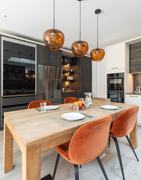 Kitchen and dining area with wooden table, rust velvet chairs and amber pendant lights, photographed for Simple Interiors in Fulham, London.