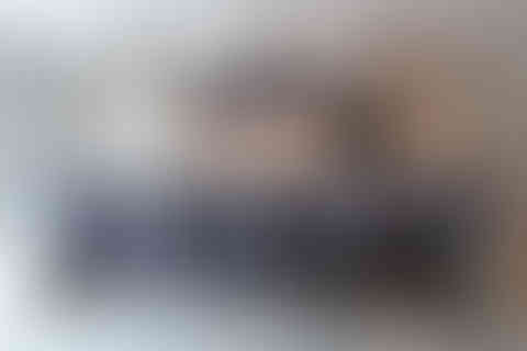 Wide view of modern kitchen with marble island, upholstered bar stools and pendant lighting.