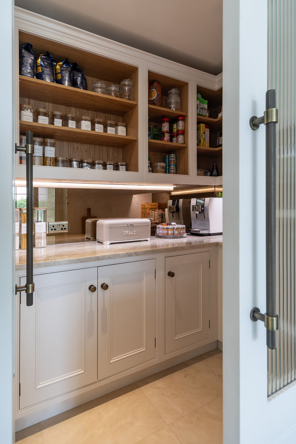 Detail of kitchen pantry shelving with warm lighting and glass storage