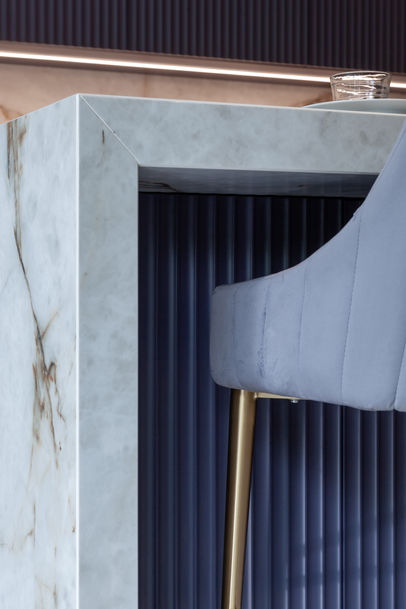 Close-up of marble waterfall edge on kitchen island with navy fluted panel detail