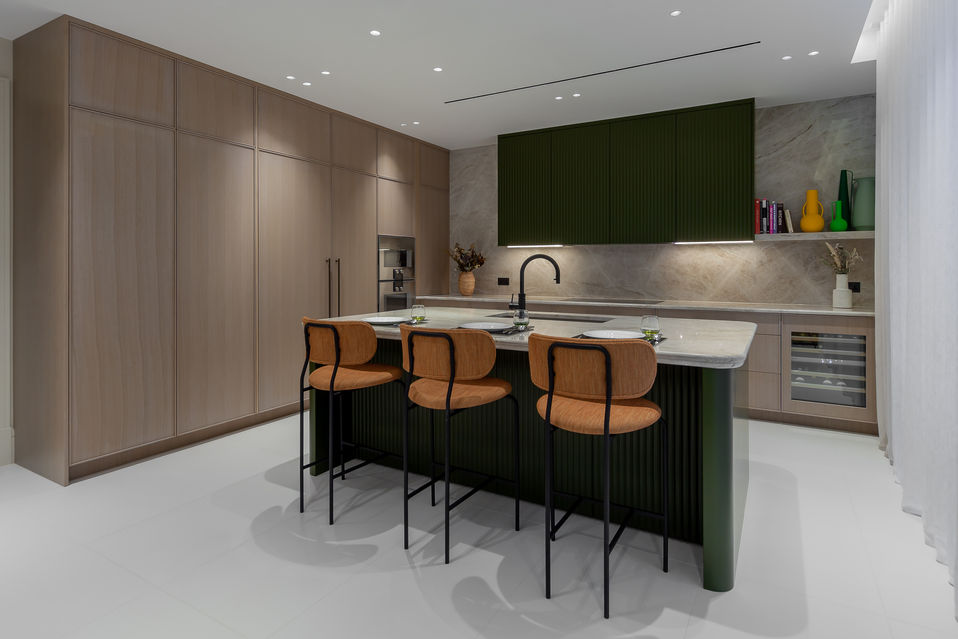 Full view of contemporary kitchen with deep green island, light timber cabinets and integrated appliances