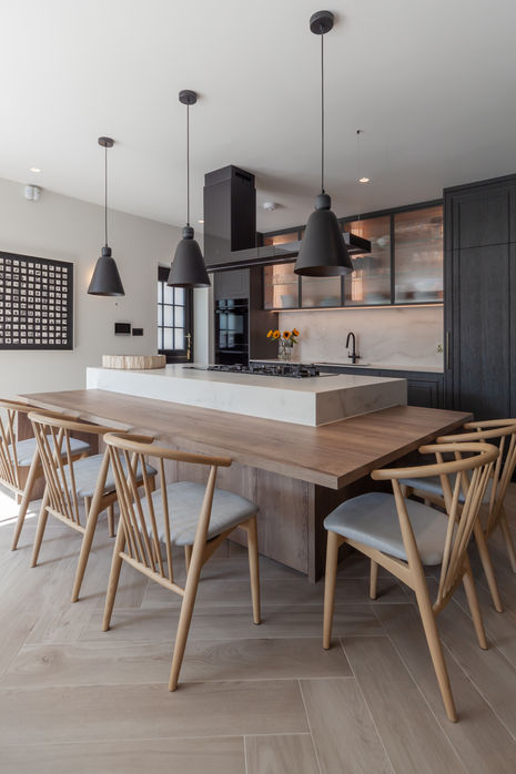 Modern kitchen and dining area with timber table, island seating and pendant lights in Queen’s Park, London.