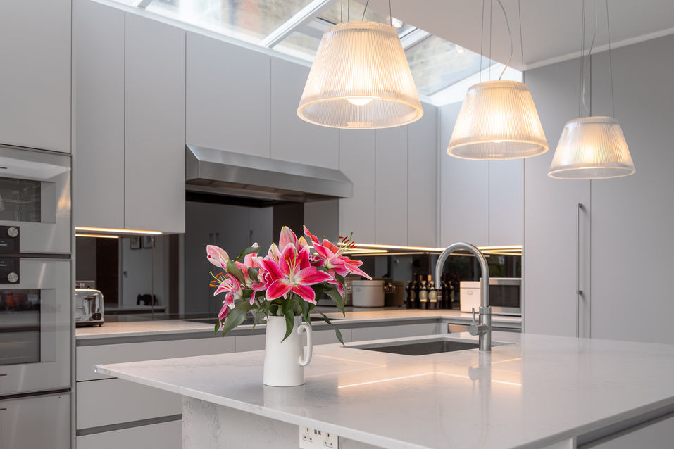 Trio of pendant lights above a modern kitchen island with flowers as a focal point.