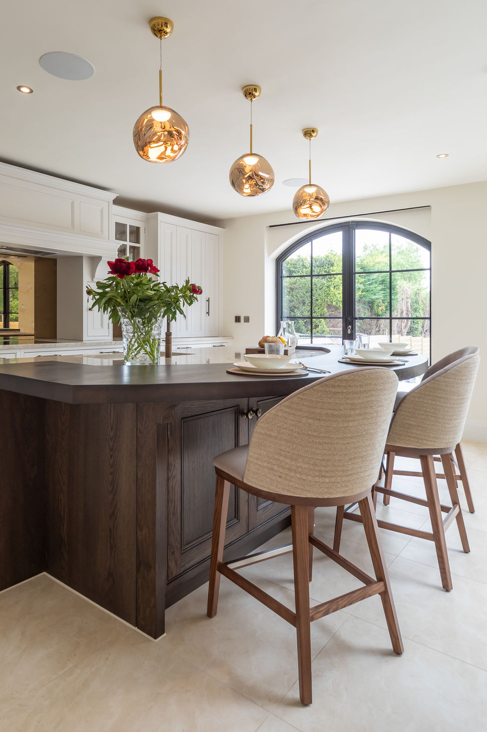 Kitchen island seating area with timber stools and warm brass pendant lighting