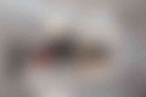 Wide-angle view of a bright white kitchen with grey cabinetry, a large island, and pendant lights.