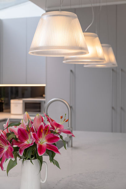 Close-up of pendant lights above the worktop with pink flowers in the foreground.