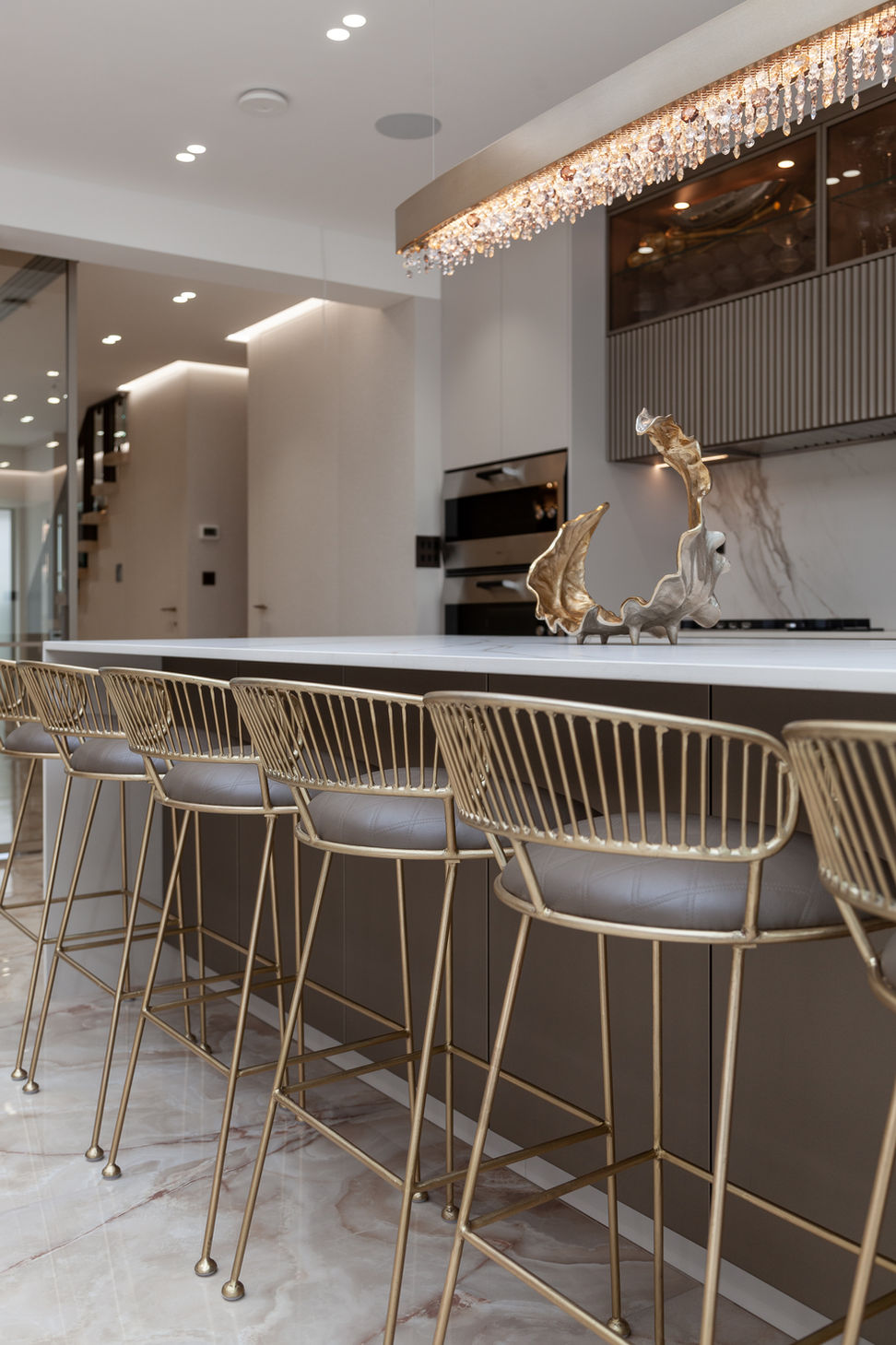 Side angle of the kitchen island with bar stools and feature lighting, showing depth and perspective.