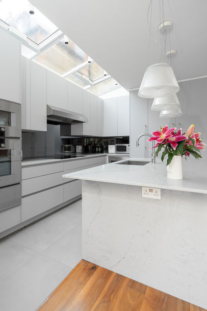 Bright open-plan kitchen with skylight, white cabinetry, and island styled with flowers.