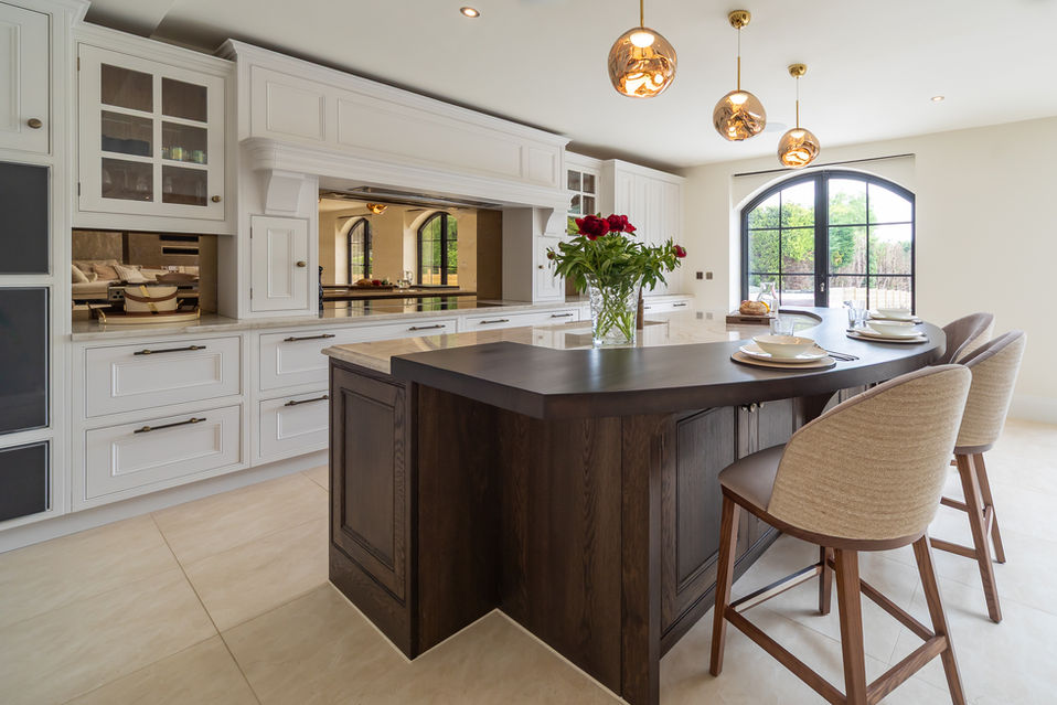 Angled view of timber island with classic white cabinetry and arched window light
