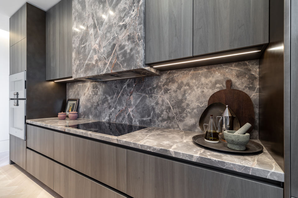 Modern handleless kitchen runs with marble worktop and splashback, under-cabinet lighting and a styled niche.