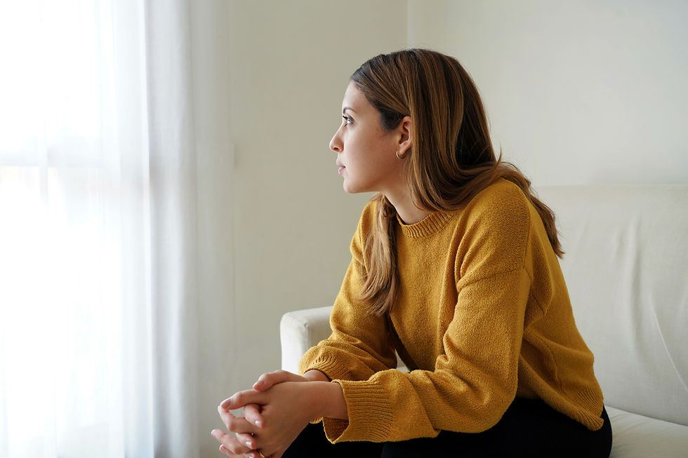 Woman sitting by a window in reflection, representing the connection between hormones and mental health.