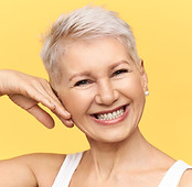 studio-shot-charismatic-positive-middle-aged-female-posing-against-yellow-background-touch
