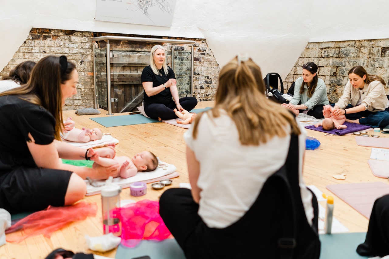 a group of mums and babies sitting around a teacher in a baby massage class in ware hertfordshire
