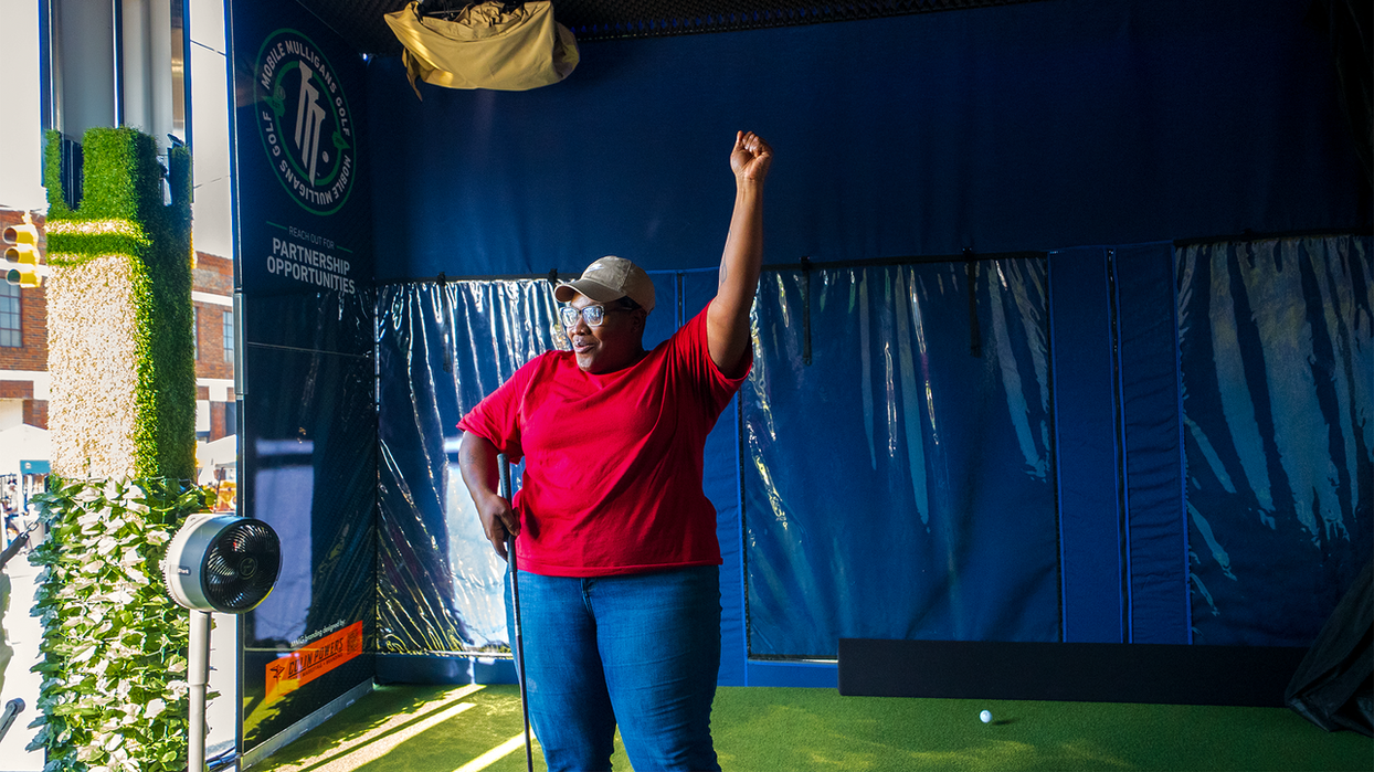 A guest raises an arm in celebration inside the Mobile Mulligans hitting bay