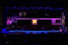 Modern dining area at Jade Eatery & Lounge in Forest Hills, Queens with neon “Indulge Your Senses” sign and Buddha décor