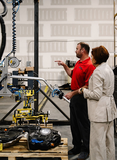 Man explaining machinery to woman in factory