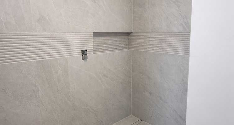 Custom curbless shower installation featuring large format porcelain tile, precision miters, linear drain, and a fully waterproofed Schluter® system.