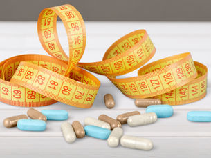 Fat burning, weight loss pills next to a yellow waist measuring tape