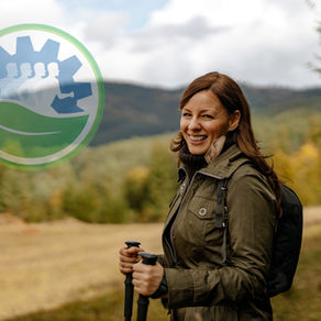 Woman standing on a hill using walking sticks to hike and smiling.
