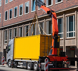 Kranbil som lastar av gul 20ft container