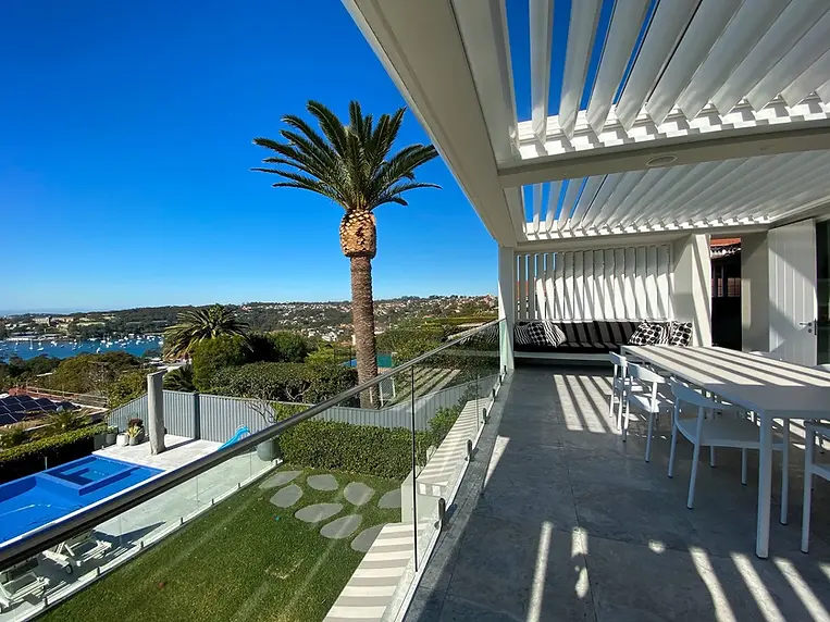 Modern outdoor living space with pool, palm tree, harbor view, sunny day with Stamfords Louvres installed