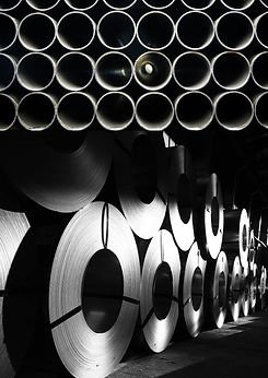 Metal coils stacked in a warehouse, dramatic lighting.
