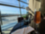 Glass of rosé on a table with a white napkin and potted orchid. Airport runway visible through large windows in the background.