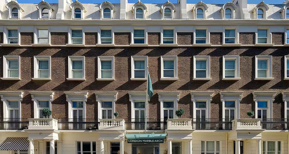 Ornate brick hotel facade with rows of white-framed windows and green awnings; sign reads LONDON MARBLE ARCH.