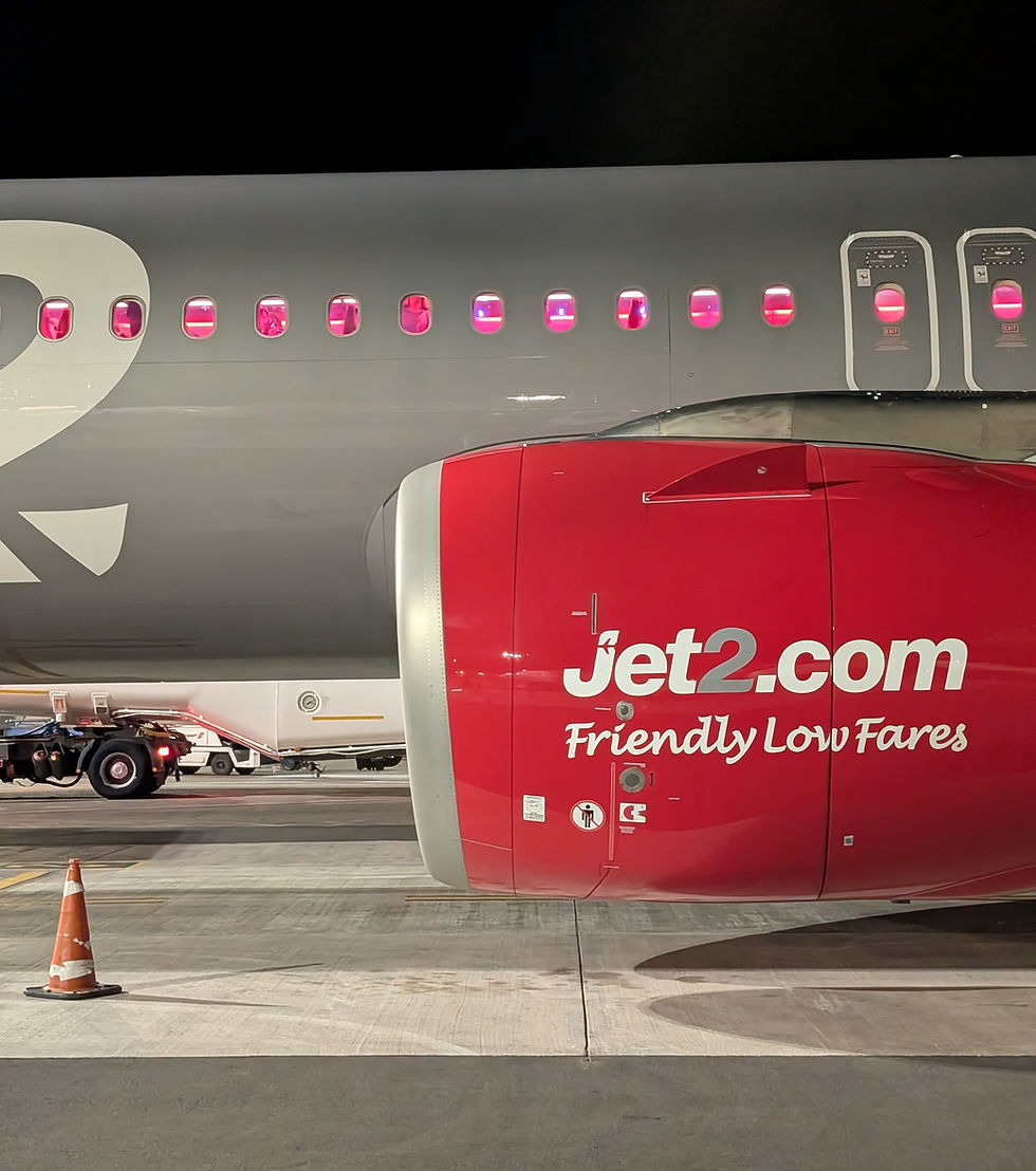 Jet2 plane at night on the tarmac, red engine and cabin windows glowing pink, with Friendly Low Fares logo visible.
