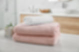Fresh towels and salt on white table in bathroom.jpg