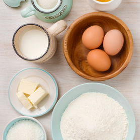 Baking essentials gathered: flour, eggs, milk, sugar, butter, and oil ready for a delicious dessert creation.