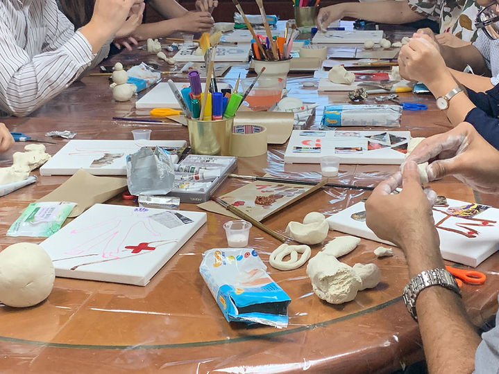 An image of an office that has been transformed into an art studio for a day where the staff explores clay, canvas painting