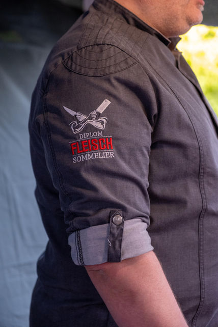 Seitlicher Blick auf eine Kochjacke mit dem Stick der Diplom Fleischsommeliers
