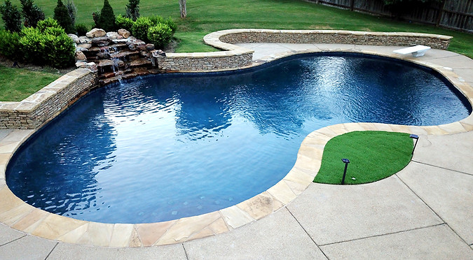 Custom pool with stone waterfall, lush landscaping, and elegant hardscape design.