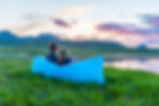 A couple sits on an inflatable couch by a mountain lake at sunset..jpg