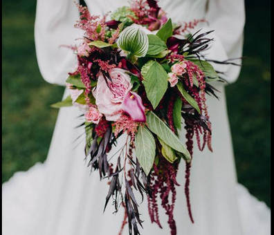 bride holding a bouquet of Hanging amaranthus with orchids, astilbe and lots of greens