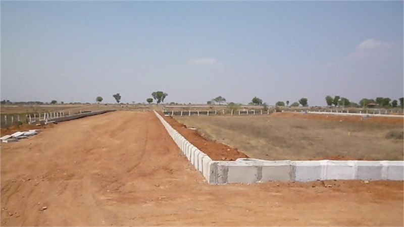 Open dirt land with road and concrete wall