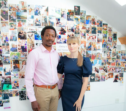 Male and female care managers, standing in front of a wall of client photos.
