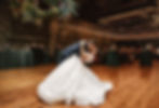 A groom dipping his bride in their beautiful wedding clothes, fairy lights overhead