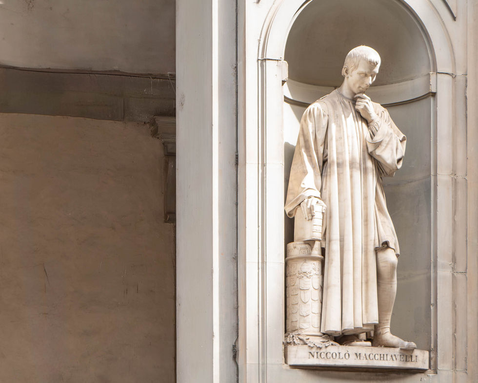 Statue of a robed figure standing in an arched niche, one hand on the chin and the other holding a scroll; classical architectural detailing surrounds the figure, suggesting a scholarly or philosophical tribute.